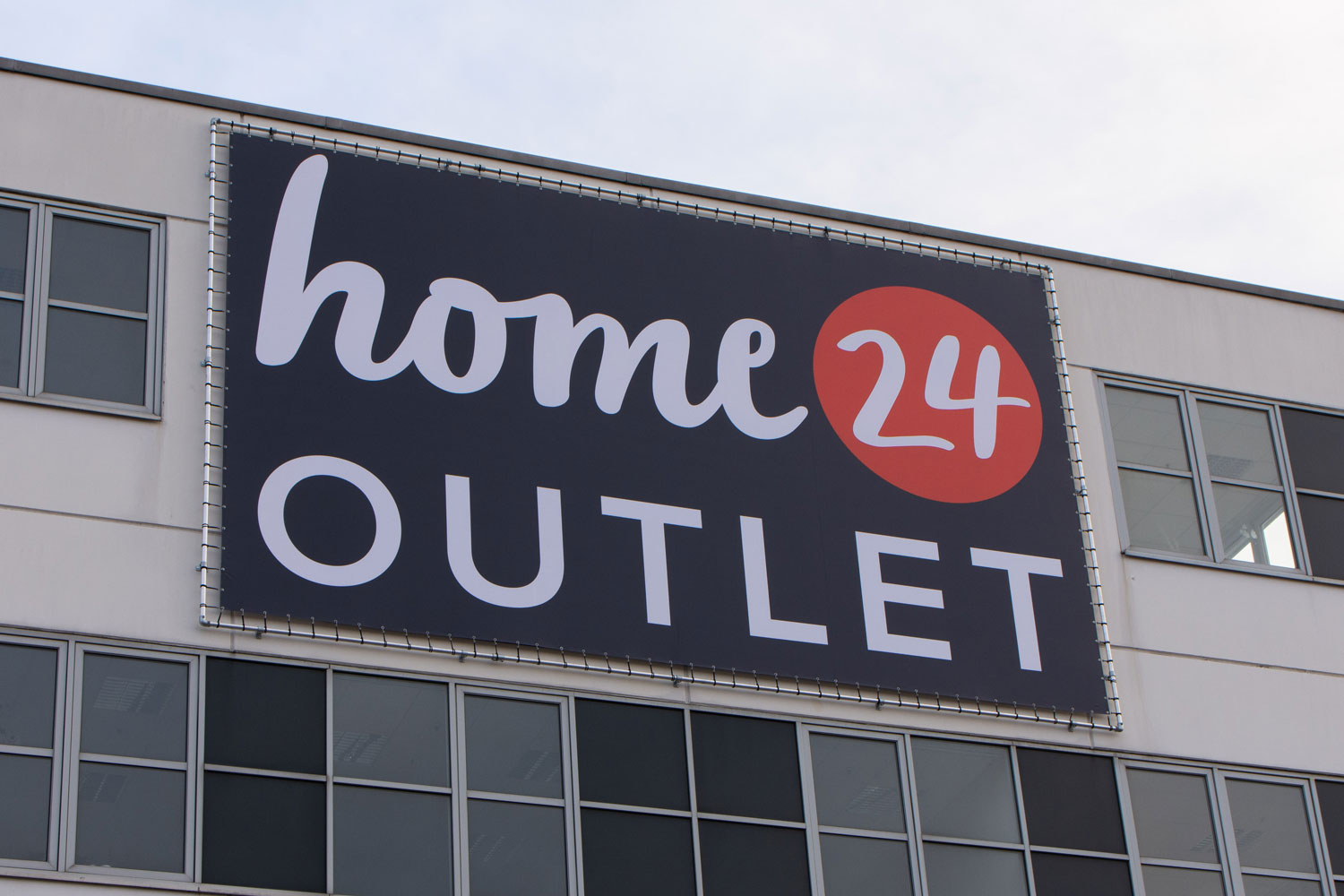 Großformatiges Fassadenbanner an Gebäude mit umlaufender Rahmenkonstruktion befestigt